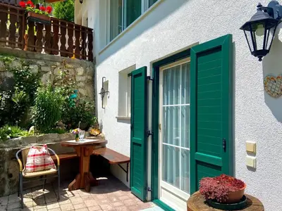 a patio with a table and a green door at Apartment Cesa Vedla DOLOMITES by Interhome in Bulla