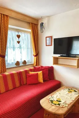 a living room with a red couch and a table at Apartment Cesa Vedla DOLOMITES by Interhome in Bulla