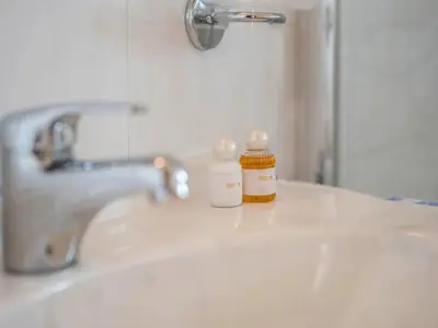 two bottles of medicine sitting on top of a bathroom sink at Apartment Morgensonne by Interhome in Maranza