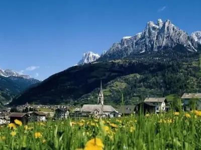a village with a church and mountains in the background at Holiday Home Romantisches Chalet in den Wiesen der Dolomiten by Interhome in Mezzano