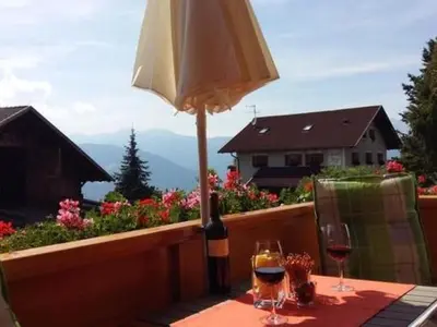 a table with a bottle of wine and an umbrella at Apartment Wohnung Valentin by Interhome in Meltina