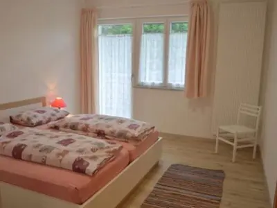 a bedroom with a bed and a chair and a window at Apartment Moderne Ferienwohnung mit Balkon und Pool by Interhome in Merano