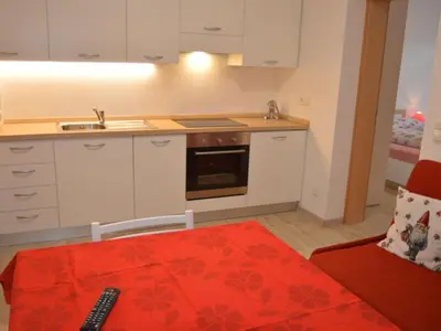 a kitchen with white cabinets and a red rug at Apartment Moderne Ferienwohnung mit Balkon und Pool by Interhome in Merano
