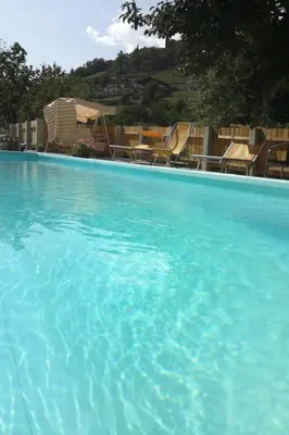 a large pool of blue water with chairs in it at Apartment Moderne Ferienwohnung mit Balkon und Pool by Interhome in Merano