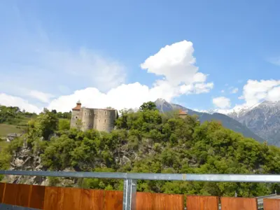 a castle on a hill with mountains in the background at Apartment Moderne Ferienwohnung mit Balkon und Pool by Interhome in Merano