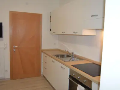 a kitchen with a sink and a wooden door at Apartment Moderne Ferienwohnung mit Balkon und Pool by Interhome in Merano