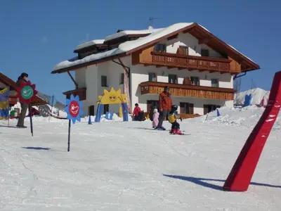 a ski lodge with people in the snow in front at Apartment Rosenheim Appartement 4 by Interhome in Maranza