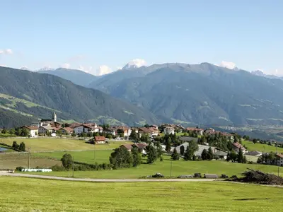a village in a field with mountains in the background at Apartment Rosenheim Appartement 4 by Interhome in Maranza