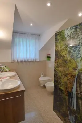 a bathroom with two sinks and a toilet and a painting at Apartment Bergblick by Interhome in Castelvecchio