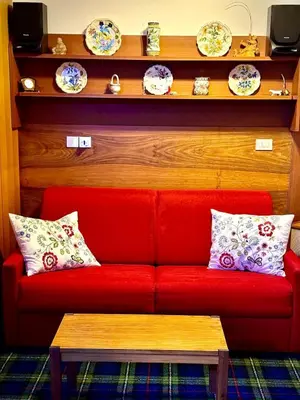 a red couch in a room with plates on a shelf at Apartment in the center of Cortina with private garage in Cortina dʼAmpezzo