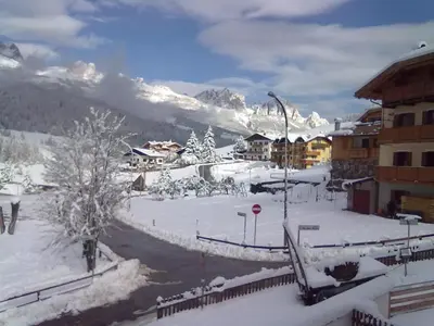a snow covered village with a mountain in the background at El Ladinia Someda in Moena