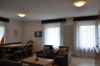 a living room with a table and chairs and curtains at El Ladinia Someda in Moena