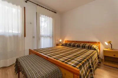 a bedroom with a bed with a plaid blanket and a window at Petit Cirsio in Santa Fosca