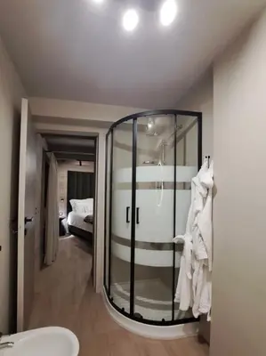 a bathroom with a glass shower with a bed at VHĀUS Apartment and Spa in Predazzo