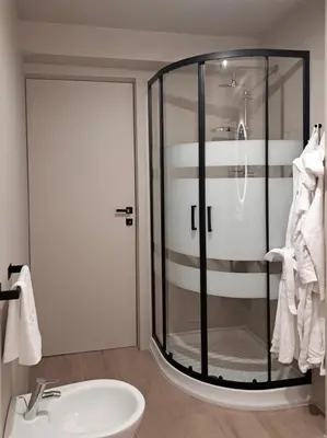 a bathroom with a glass shower and a sink at VHĀUS Apartment and Spa in Predazzo
