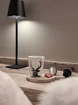 a table with a lamp and a cup on it at VHĀUS Apartment and Spa in Predazzo