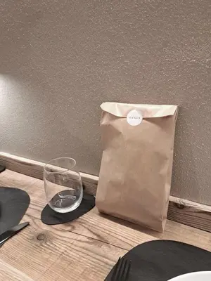 a paper bag sitting on a table next to a glass at VHĀUS Apartment and Spa in Predazzo