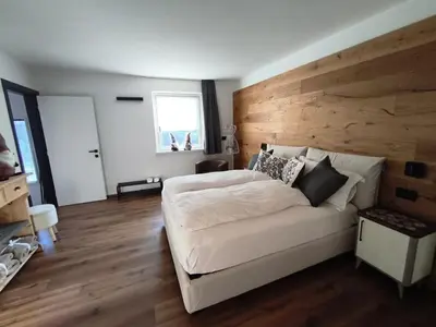 a bedroom with a white bed and a wooden wall at Nemus Alpine Living in Cavalese