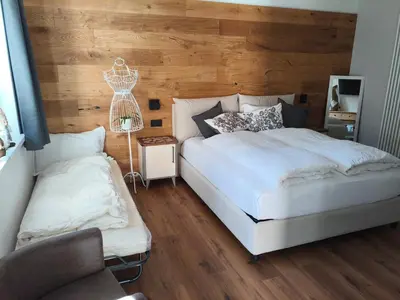 a bedroom with a white bed and a wooden wall at Nemus Alpine Living in Cavalese