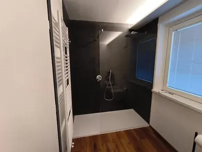 a bathroom with a shower with a black wall at Nemus Alpine Living in Cavalese