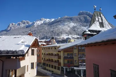 a group of buildings with snow covered mountains in the background at Sky Loft at Cervo - Panoramic Penthouse in Moena in Moena