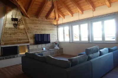 a living room with couches and a tv and a fireplace at Sky Loft at Cervo - Panoramic Penthouse in Moena in Moena