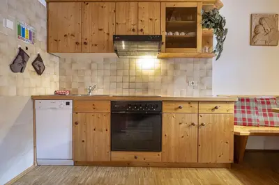 a kitchen with wooden cabinets and a white dishwasher at Apartments Romy in Ortisei