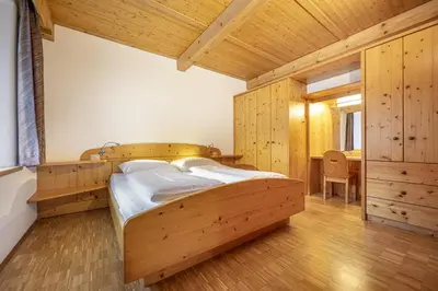 a bedroom with two beds in a room with wooden walls at Apartments Romy in Ortisei