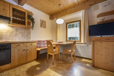 a kitchen with a table and chairs and a tv at Apartments Romy in Ortisei