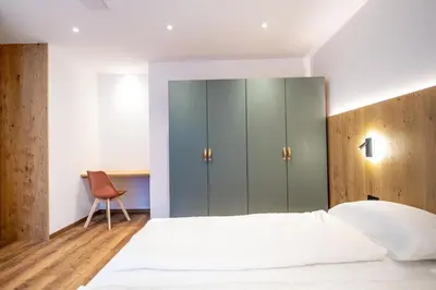 a bedroom with a bed and a cabinet at Tito Apartments in Ortisei