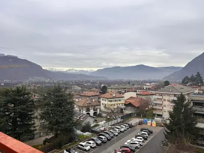 a city with cars parked in a parking lot with mountains at Casa Iris in Laives