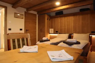 a room with two beds and a wooden table at Ciesa Le Crepedele Miniappartamento Mirandola in Sottoguda