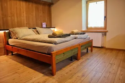 a bed with a wooden frame in a room at Ciesa Le Crepedele Miniappartamento Mirandola in Sottoguda