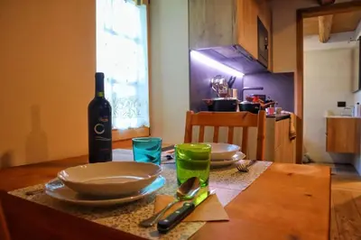 a table with a bottle of wine and plates and glasses at Ciesa Le Crepedele Miniappartamento Mirandola in Sottoguda