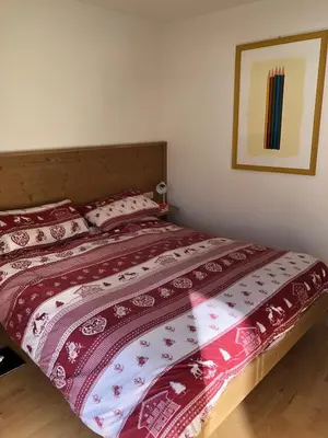 a bed with a red and white comforter on it at Appartamento panoramico vicino al Kronplatz in Riscone