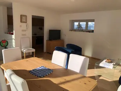 a dining table and chairs in a living room at Appartamento panoramico vicino al Kronplatz in Riscone