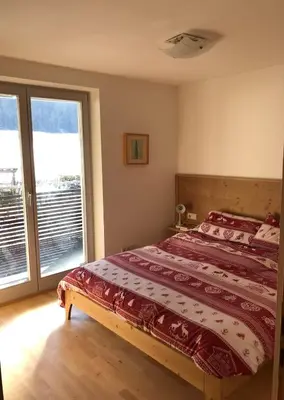 a bedroom with a bed and a large window at Appartamento panoramico vicino al Kronplatz in Riscone