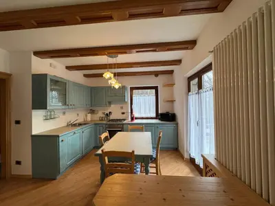 a kitchen with blue cabinets and a table with chairs at Villetta rifugio tra i larici in Varena