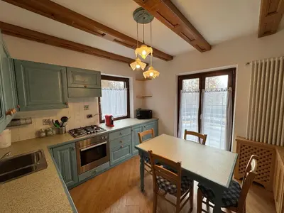 a kitchen with green cabinets and a table with chairs at Villetta rifugio tra i larici in Varena
