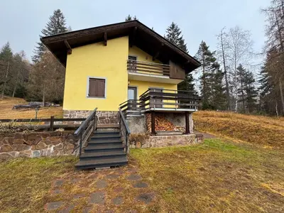 a yellow house with a staircase in front of it at Villetta rifugio tra i larici in Varena
