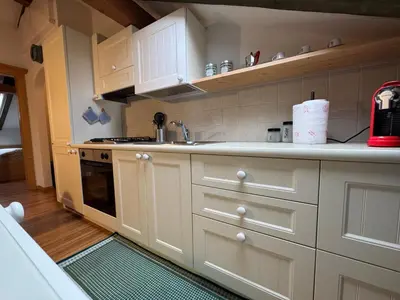 a kitchen with white cabinets and a stove top oven at Villetta rifugio tra i larici in Varena
