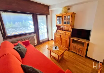 a living room with a red couch and a television at HT - Appartamento centrale nel cuore delle Dolomiti in San Vito di Cadore