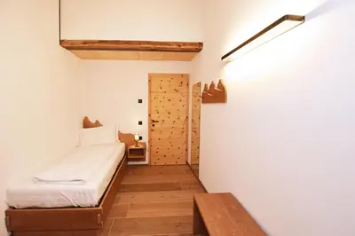 a small bedroom with a bed and a wooden table at Aurturist Moar - San Lorenzo di Sebato in Floronzo