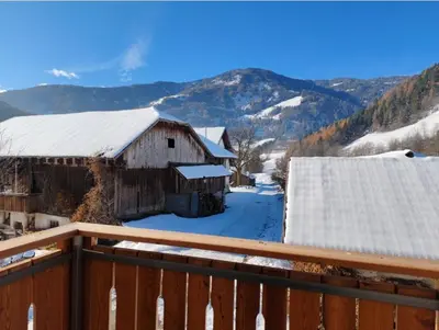 a snow covered barn with mountains in the background at Aurturist Moar - San Lorenzo di Sebato in Floronzo
