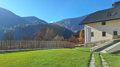 a yard with a fence and a house and mountains at Aurturist Moar - San Lorenzo di Sebato in Floronzo