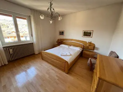 a bedroom with a bed and a table and a window at A Due Passi dalle Piste in Cavalese