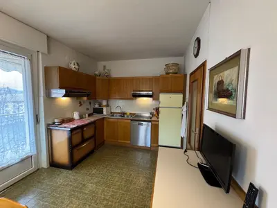 a kitchen with wooden cabinets and a large window at A Due Passi dalle Piste in Cavalese