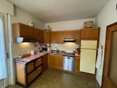 a kitchen with wooden cabinets and a refrigerator at A Due Passi dalle Piste in Cavalese