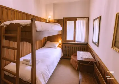 a bedroom with two bunk beds and a table at HT - Ciasa Ca' Novella nel cuore delle Dolomiti in San Vito di Cadore