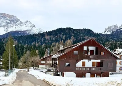 a house in the snow with mountains in the background at HT - Ciasa Ca' Novella nel cuore delle Dolomiti in San Vito di Cadore